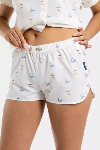 Short femme en popeline de coton rayé, orné de motifs plagiste bronzette. Pièce estivale originale, légère et confortable pour un look chic et balnéaire.
